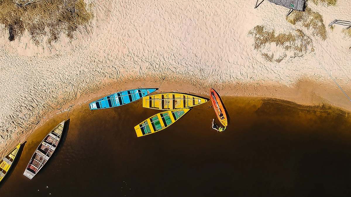 praia do sagi aerial photography of six wooden boats on calm body of water near seashore at daytime drone view